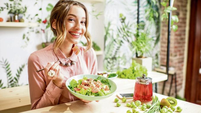 352804_stockphotoyoungwomaneatinghealthyfoodsittinginthebeautifulinteriorwithgreenflowersonthe1028139955_share